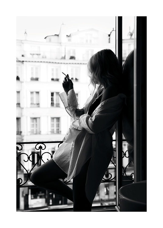  – Čiernobiela fotografia ženy vo veľkej košeli s cigaretou v okne