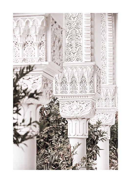  - Fotografia bielych stĺpov s detailnými vzormi a zelenými listami v pozadí