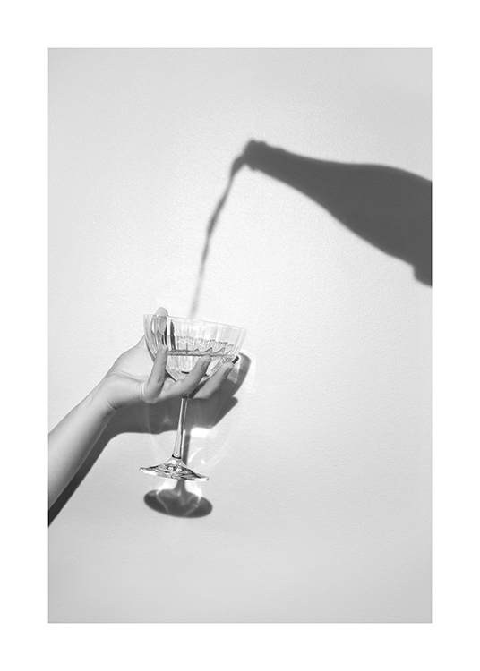  – Šedá fotografia tieňa fľaše a ruky držiacej pohár šampanského