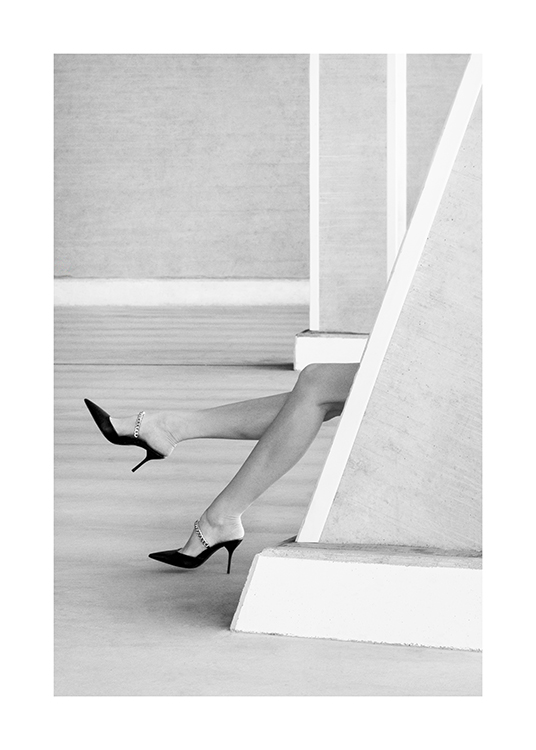 – Čiernobiela fotografia nôh s vysokými podpätkami, ktoré trčia spoza steny